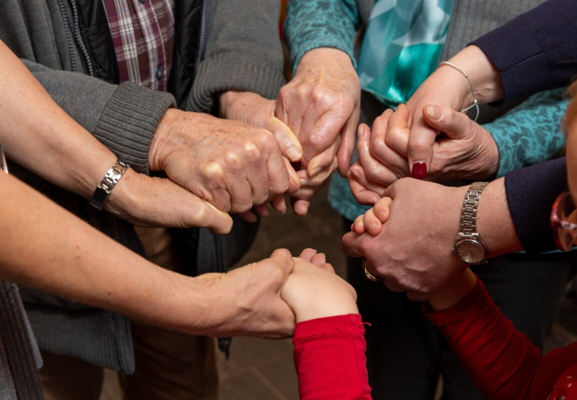 Mehrere Menschen halten sich an den Händen, symbolisieren Zusammenhalt und Gemeinschaft.